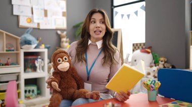 Anaokulunda hikaye kitabı okuyan güzel İspanyol bir anaokulu öğretmeni.