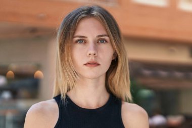 Sokakta ciddi bir ifadeyle duran genç sarışın kadın.