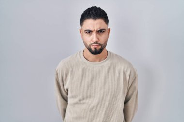 Tecrit edilmiş arka planda duran genç yakışıklı adam şüpheci ve gergin, sorun yüzünden üzgün. Negatif kişi. 