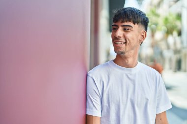 Young hispanic man smiling confident looking to the side at street