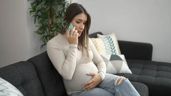 Mladá Těhotná Žena Mluví Smartphone Vážným Výrazem Doma — Stock fotografie