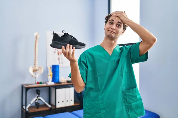 Mladý Muž Pracující Fyzioterapeutické Klinice Drží Botu Stresu Frustrovaný Rukou — Stock fotografie