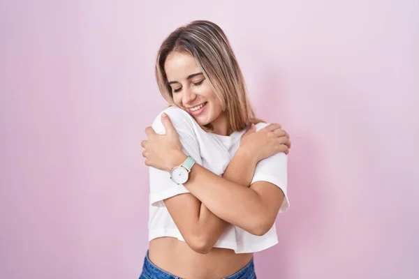Young Blonde Woman Standing Pink Background Hugging Oneself Happy Positive — Stockfoto