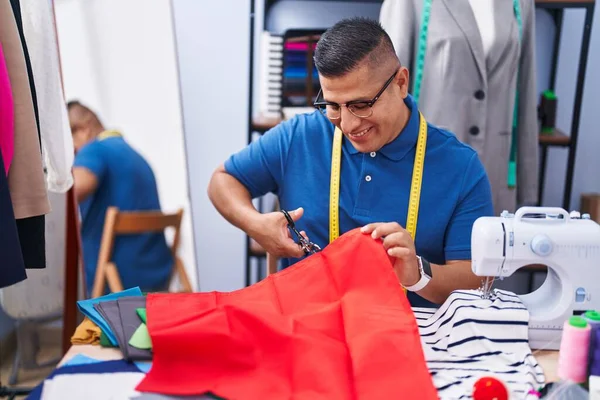 年轻的拉丁男人裁缝店裁缝师自信地微笑着裁剪布料 — 图库照片