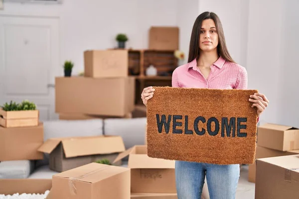 Young Hispanic Woman Holding Welcome Doormat New Home Relaxed Serious — ストック写真