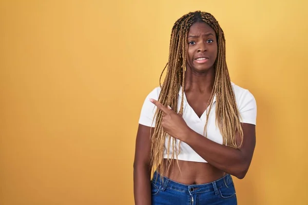 Africká Američanka Vlasy Spletenými Přes Žluté Pozadí Ukazuje Stranou Ustaraný — Stock fotografie
