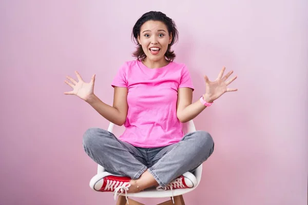Spaanse Jonge Vrouw Zit Stoel Roze Achtergrond Vieren Gek Verbaasd — Stockfoto
