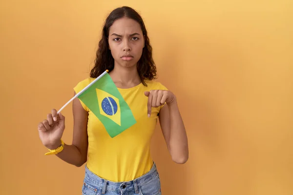 指で方向を示す 悲しいと動揺を指してブラジルのフラグを保持若いヒスパニックの女性は 不幸なと落ち込んで — ストック写真