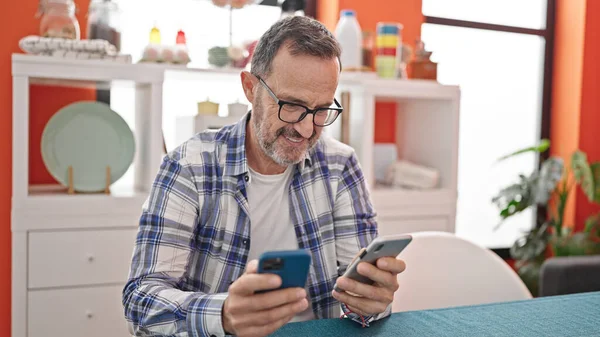 Hombre Mediana Edad Usando Teléfonos Inteligentes Sentados Mesa Comedor —  Fotos de Stock