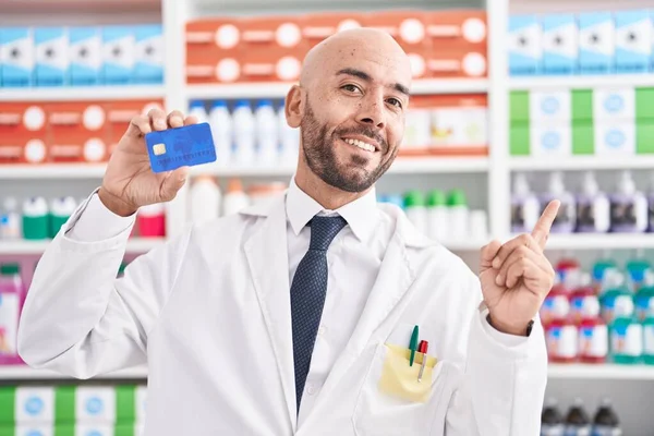 Middle Age Bald Man Working Pharmacy Drugstore Holding Credit Card — Stock Photo, Image