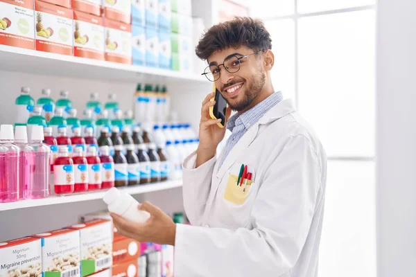 Młody Arabski Aptekarz Rozmawia Smartfonie Trzymając Butelkę Tabletek Aptece — Zdjęcie stockowe