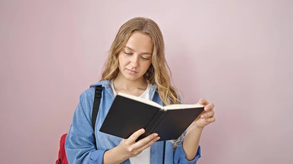 Giovane Studentessa Bionda Lettura Libro Con Espressione Grave Sfondo Rosa — Foto Stock