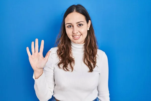 Молодая Латиноамериканка Стоящая Синем Фоне Показывающая Пальцами Номер Пять Улыбаясь — стоковое фото