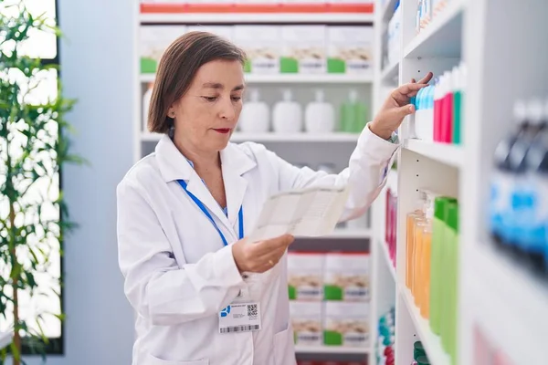 Kobieta Średnim Wieku Farmaceuta Przechowujący Receptę Odczyt Produktu Aptece — Zdjęcie stockowe