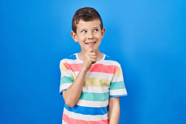 Niño Caucásico Joven Pie Sobre Fondo Azul Con Mano Barbilla —  Fotos de Stock
