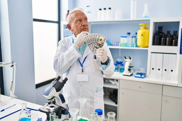 Starszy Naukowiec Siwymi Włosami Pracujący Laboratorium Trzymający Dolary Poważna Twarz — Zdjęcie stockowe