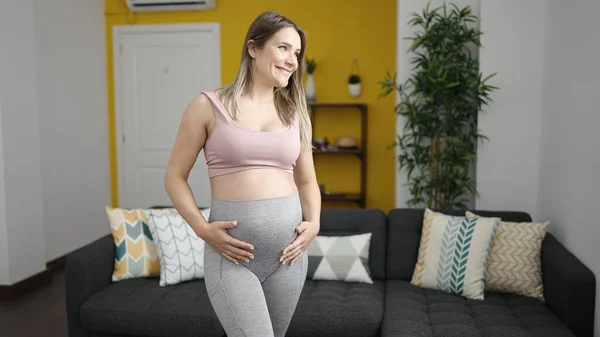 Spor Giyimli Hamile Bir Kadın Evde Karnına Dokunuyor — Stok fotoğraf