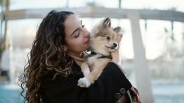 Parkta gülümseyen köpeği olan genç İspanyol kadın.