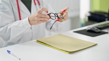 Genç sarışın doktor klinikte gözlük takarak gülümsüyor.
