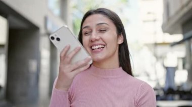 Genç, güzel İspanyol kadın sokakta akıllı telefonuyla sesli mesaj yolluyor.
