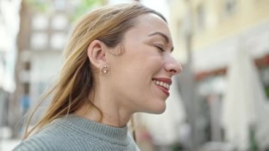 Kahve dükkanının terasında gözleri kapalı nefes alan genç sarışın kadın.