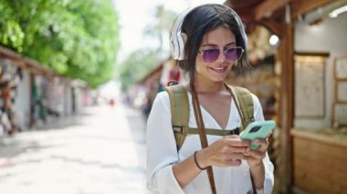 Genç, güzel İspanyol kadın turist. Kendine güvenen, sokak pazarında müzik dinleyen.