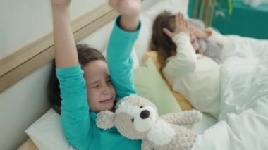 Sevimli kızlar yatak odasında kollarını esneterek uyanıyorlar.