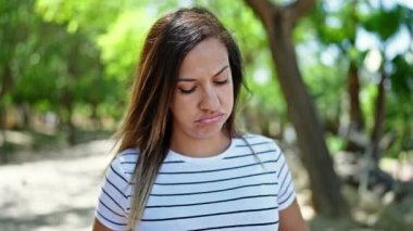 Orta Doğulu kadın üzgün bir ifadeyle parkta dikiliyor.