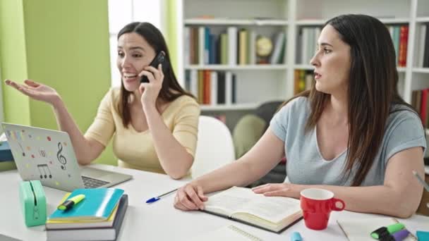 Duas Mulheres Estudo Perturbador Para Conversa Smartphone Universidade Biblioteca — Vídeo de Stock
