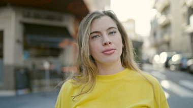 Sokakta rahat bir ifadeyle duran genç sarışın kadın.
