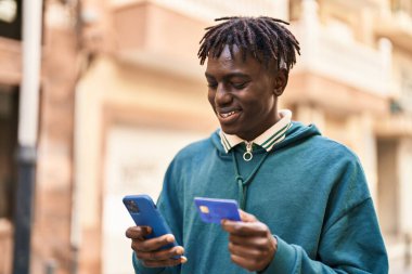 Sokakta akıllı telefon ve kredi kartı kullanan Afrikalı bir Amerikalı.