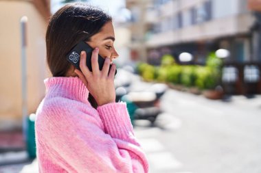 Genç İspanyol kadın gülümsüyor. Kendine güveniyor. Akıllı telefondan konuşuyor.