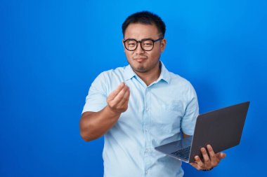 Bilgisayarı kullanan Çinli genç adam elleriyle para hareketi yapıyor, maaş istiyor, milyonerlik işi yapıyor. 