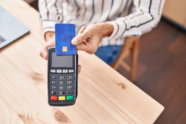 Genç İspanyol adam kredi kartıyla ödeme yapıyor.