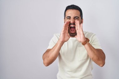 Sakallı İspanyol adam izole edilmiş arka planda duruyor ve elleri ağzında bağırıyor. 