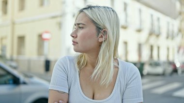 Young beautiful hispanic woman looking to the side with serious expression at street