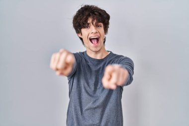 Young man standing over isolated background pointing to you and the camera with fingers, smiling positive and cheerful 