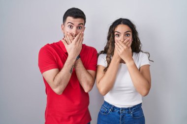 Tecrit edilmiş arka planda duran genç İspanyol çift yanlışlıkla ağızlarını kapatarak şok geçirdiler. gizli kavram. 