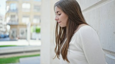 Young beautiful hispanic woman looking to the side with serious expression at street