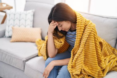 Young hispanic girl stressed sitting on sofa at home