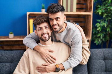 Young couple hugging each other sitting on sofa at home