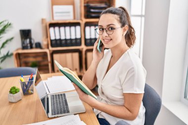 Genç, güzel İspanyol iş kadını. Ofiste akıllı telefondan kitap okuyor.