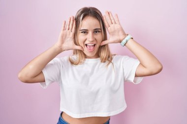 Pembe arka planda duran genç, sarışın bir kadın gülümseyen, güler yüzlü, elleri havada dikizleme oyunu oynayan. Şaşırdım ve çıktım. 