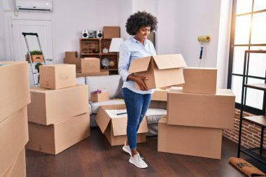 African american woman smiling confident holding package at new home