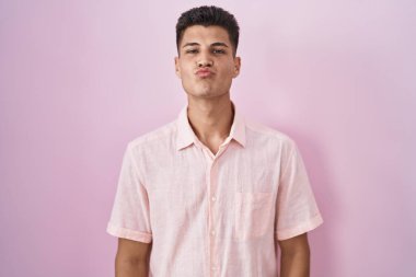 Genç İspanyol bir adam pembe arka planda dikilip kameraya bakıyor. Canlı yayında öpücük yolluyor. Güzel ve seksi. aşk ifadesi. 