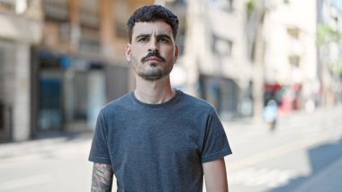 Sokakta ciddi bir ifadeyle duran İspanyol genç adam.