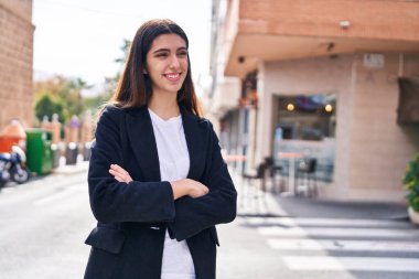 Sokakta kollarını kavuşturmuş genç, güzel İspanyol bir kadın.