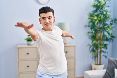 Young non binary man doing yoga exercise sitting on floor at home