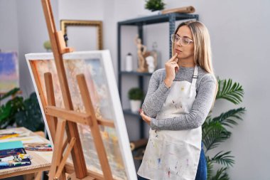 Young woman artist looking draw with doubt expression at art studio