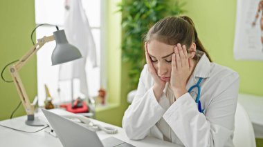 Young beautiful hispanic woman doctor stressed working at clinic